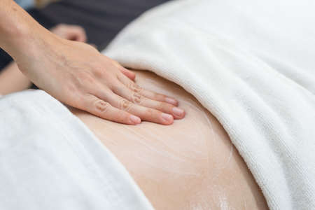 Massage series : Therapist applying cream on woman's stomachの写真素材