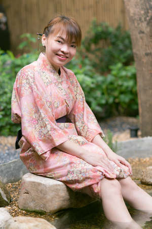 Lifestyle series : Asian woman in yukata, sitting in Asian gardenの写真素材