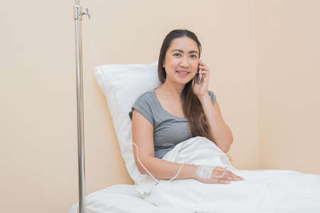 Healthcare series : Asian female making phone call on hospital bedの写真素材