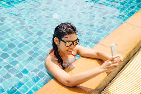 Swimming pool series : Using smart phoneの写真素材