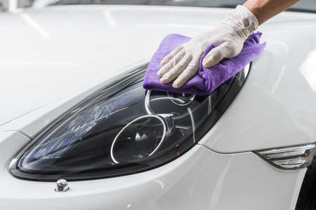 Car detailing series : Closeup of hand cleaning white carの写真素材