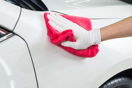 Car detailing series : Closeup of hand cleaning white carの写真素材