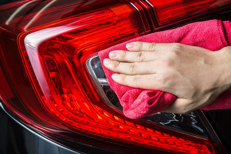Car detailing series : Closeup of hand cleaning black car taillightsの写真素材