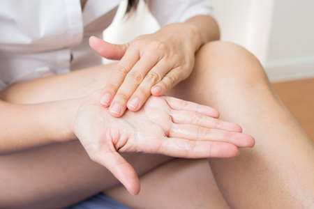 Beauty series: Asian woman applying lotion to her hands, closeupの写真素材