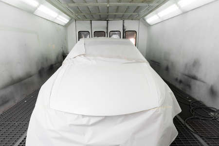 Auto body repair: Masked white car in paint boothの写真素材