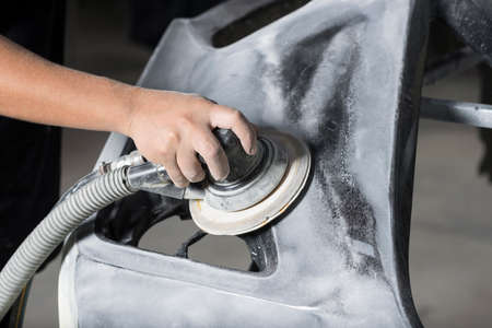 Auto body repair series: Closeup of mechanic sanding car bumperの写真素材