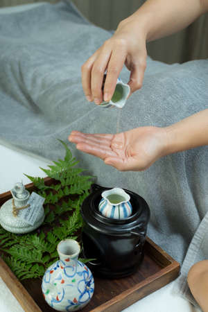 Aromatherapy massage series: Therapist pouring oil into her handsの写真素材