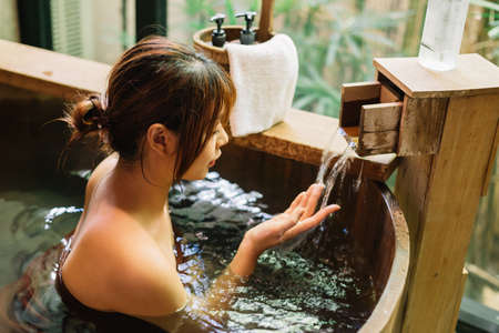 Onsen series: Asian woman taking a bath in wooden bathtubの写真素材