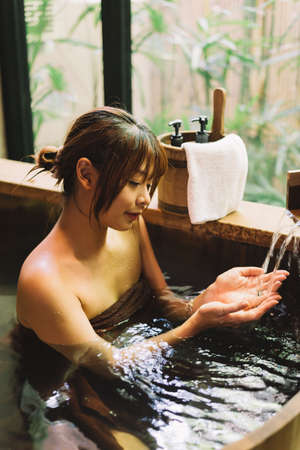 Onsen series: Asian woman taking a bath in wooden bathtubの写真素材