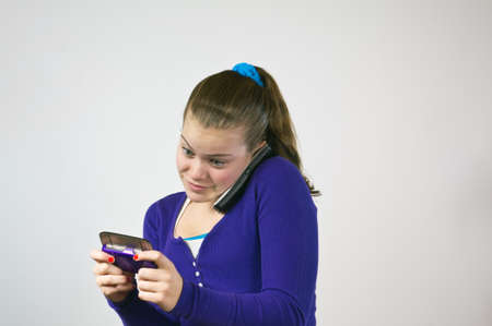 Teen girl with two phones texting and talkingの写真素材