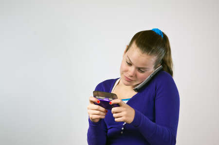 Teen girl with two phones texting and talkingの写真素材