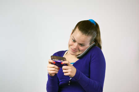 Teen girl with two phones texting and talkingの写真素材