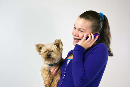 Teen girl talking on the telephone and holding a small dogの写真素材