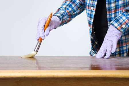 Woman sanding and varnishing a tableの写真素材