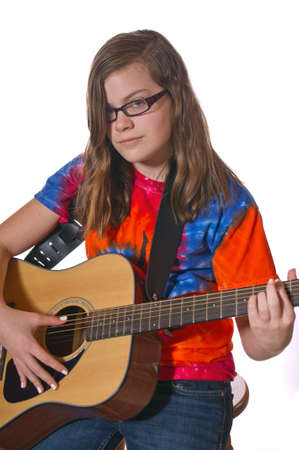 Girl on a stool playing an acoustic guitar isolated on white backgroundの写真素材