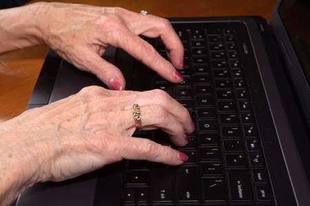 Close up of Senior citizen hands on laptop keyboardの写真素材