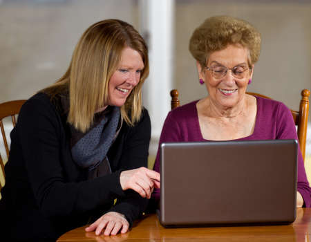Daughter teaching elderly mother to use laptopの写真素材