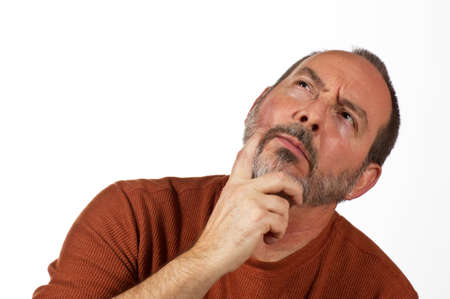 middle aged man with hand on beard looking up thinkingの写真素材