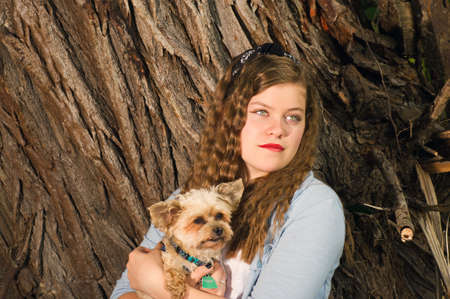 Teen Girl  in a park by an old tree, holding a small dogの写真素材