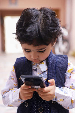 Cute Indian Boy Kid talking and Playing With Mobile Phone.の写真素材