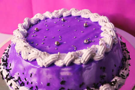 Blue purple buttercream cake with colorful sprinkles over a light grey background.の写真素材