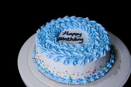 Blue buttercream cake with colorful sprinkles over a light grey background.の写真素材