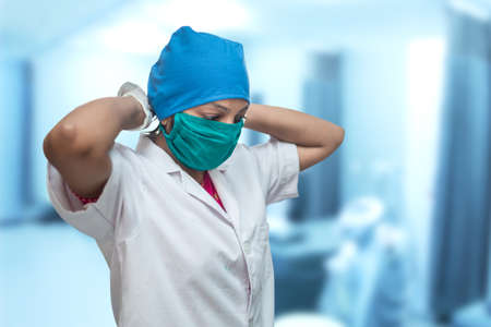 Close up of a female medical worker, nurse putting on a respirator surgical mask to protect from coronavirus, Covid-19 Pandemic.の写真素材