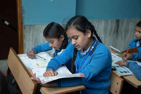Jodhpur, Rajasthan, India - Jan 10th 2020: Primary indian female students studying in the Classroom Taking Exam / Test Writing in Notebooks. education concept.のeditorial素材