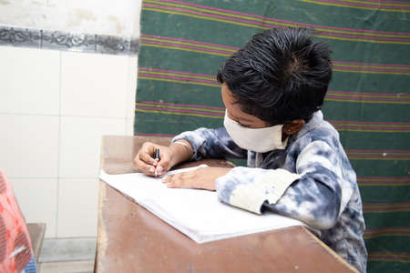 student wearing mask studying writing in classroom during covide-19 pandemic, school reopen, back to school.のeditorial素材
