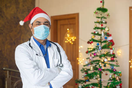 Portrait of doctor wearing mask and christmas hat celebration during covid-19 pandemic, lockdown,...