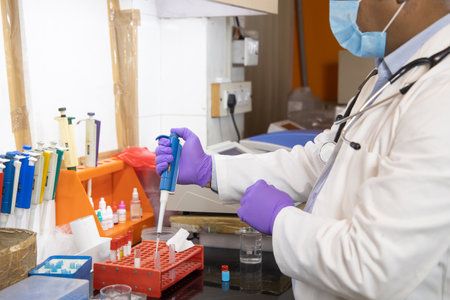 Indian medical scientist doctor wearing surgical face mask doing drug research in clinical...