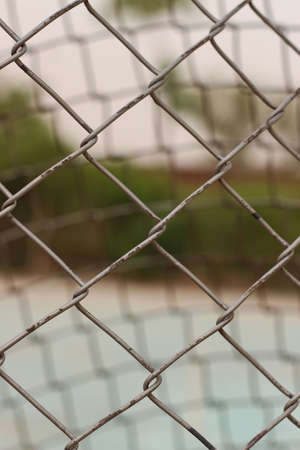 The net used outside the tennis court used to create a barrier for balls to not cross the court is captured with greenery and green court.の写真素材
