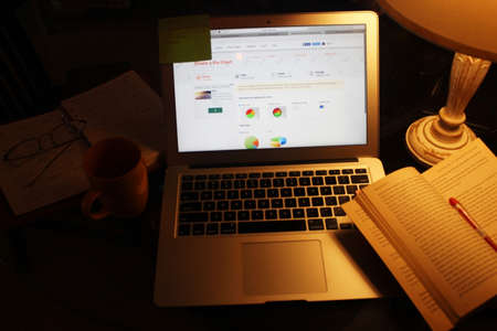 Laptop, diary, pen, sticky notes, book, table lamp, coffee mug and other supplies on the work desk...