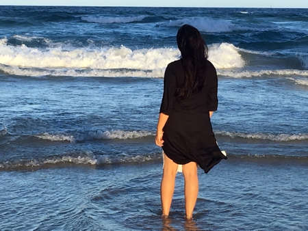 Lady walking barefoot on the beach at Gold Coast, Australia and enjoying the tropical breeze and warm sunsetの写真素材