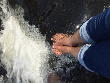 Top view of man's feet on the sand at the surf waves over them. Point of view on legs in sand with sea foam ocean summer background - Image,Vacation on ocean beach, feet on sea sand.の写真素材