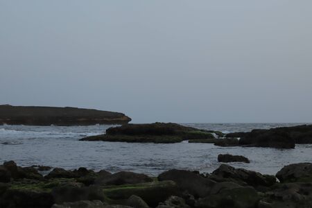 See. Beach with rocks and a cloudy sky. See Waves Touching Rocks.の写真素材