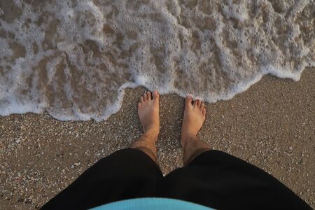 Boy on the beach sand with the water waves and water on the white sand in India.の写真素材