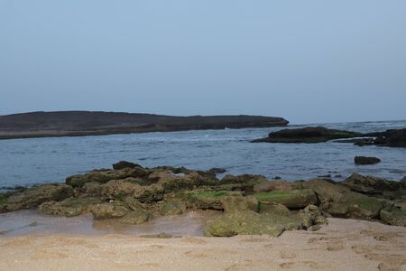 See. Beach with rocks and a cloudy sky. See Waves Touching Rocks.の写真素材