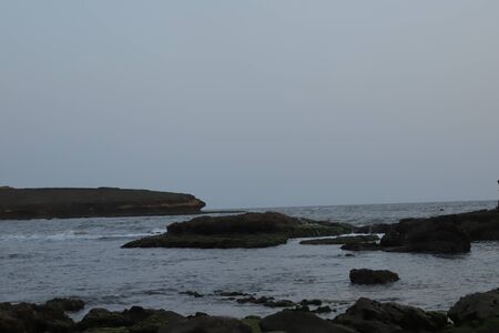 See. Beach with rocks and a cloudy sky. See Waves Touching Rocks.の写真素材