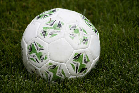 Worn White soccer ball sitting in the grassの写真素材