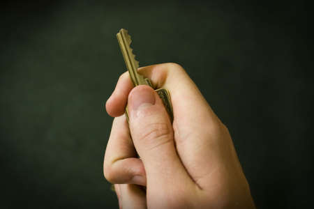 Hand Holding a Key against a black backgroundの写真素材