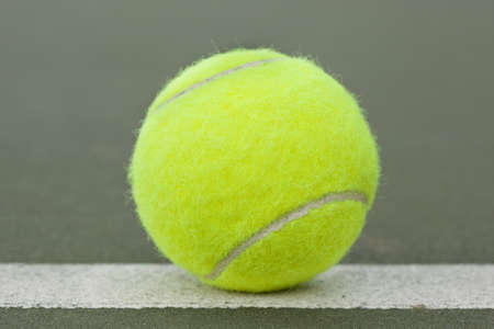A yellow tennis ball on a courtの写真素材