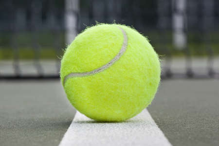 A yellow tennis ball on a courtの写真素材