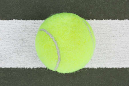 A yellow tennis ball on a courtの写真素材