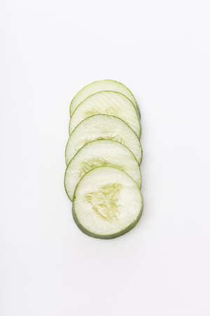 A sliced green cucumber against a white backgroundの写真素材