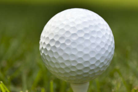 A white golf ball sitting in green grassの写真素材