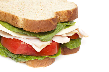 A large turkey sandwhich with tomatoes, cheese, and lettuceの写真素材