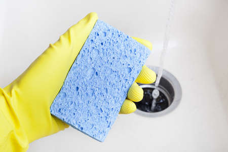 Washing a white plate with a sponge and rubber glovesの写真素材