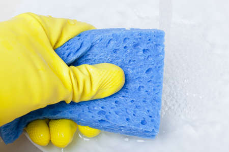 Washing a white plate with a sponge and rubber gloves