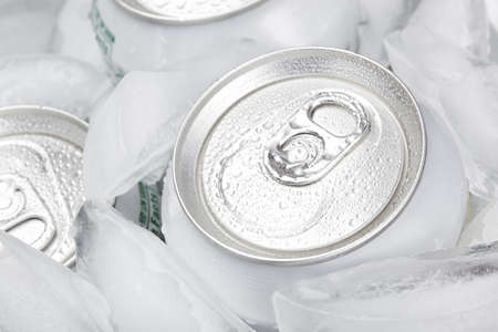 A group of soda cans in a container of iceの写真素材